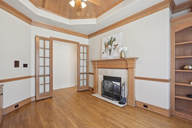 living area featuring a fireplace, french doors, a tray ceiling, and wood finished floors