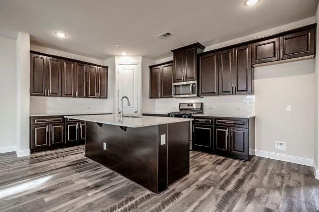 930 Estelle Dr, Euless, TX 76040 - kitchen featuring visible vents, appliances with stainless steel finishes, wood finished floors, light countertops, and a sink