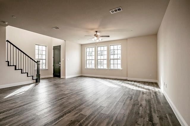930 Estelle Dr, Euless, TX 76040 - unfurnished living room featuring dark wood-type flooring, visible vents, a ceiling fan, and stairway