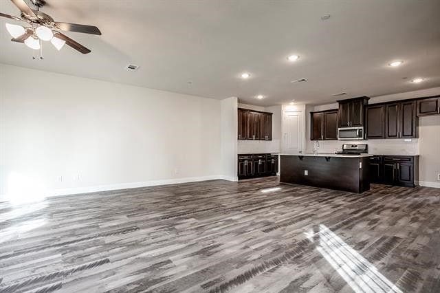 930 Estelle Dr, Euless, TX 76040 - kitchen featuring dark wood-style flooring, baseboards, open floor plan, a kitchen island with sink, and appliances with stainless steel finishes