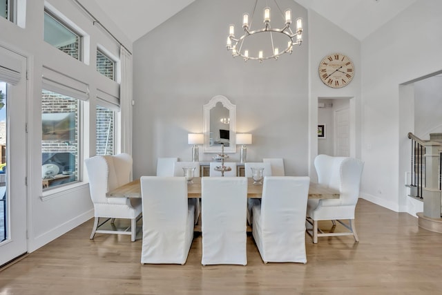 dining area with high vaulted ceiling, a chandelier, wood finished floors, and baseboards