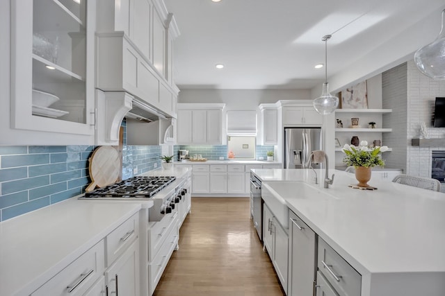 kitchen with appliances with stainless steel finishes, light countertops, an island with sink, white cabinets, and recessed lighting
