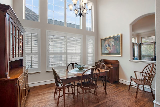 dining room featuring dark wood-type flooring, arched walkways, and plenty of natural light