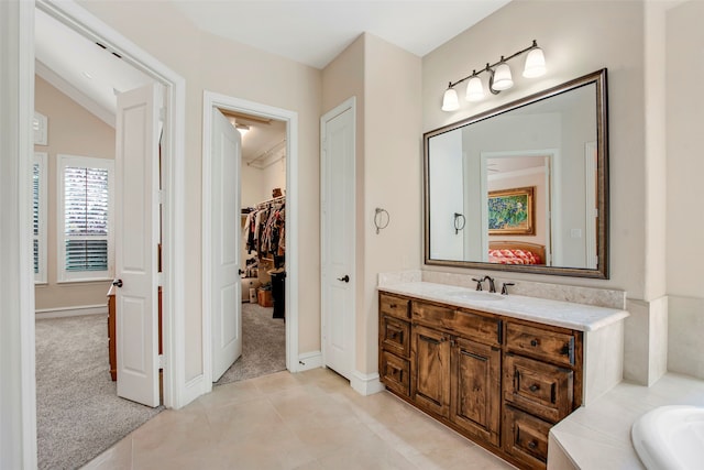 bathroom featuring tile patterned floors, a walk in closet, vanity, and vaulted ceiling