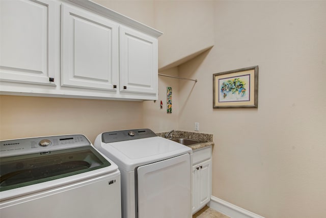 washroom featuring baseboards, a sink, cabinet space, and washer and clothes dryer