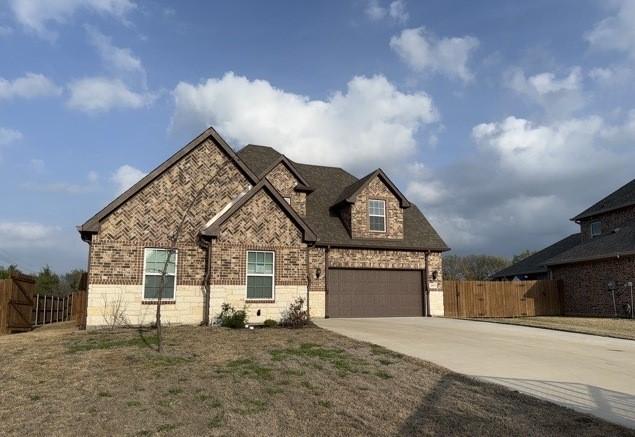 french country style house with brick siding, driveway, and fence