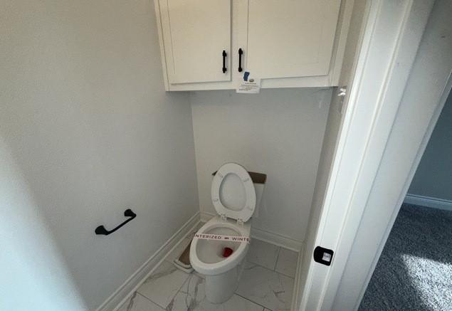 bathroom with marble finish floor, baseboards, and toilet