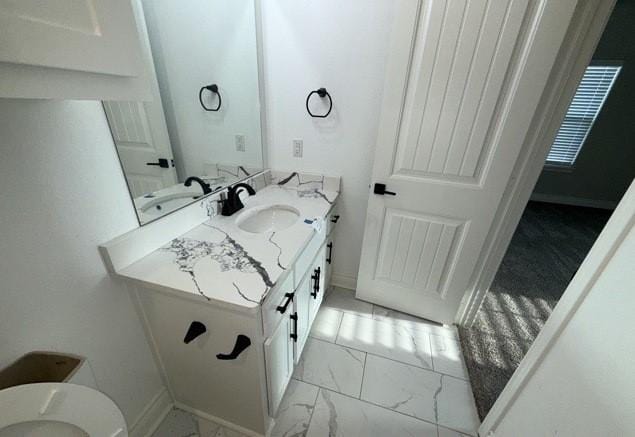 bathroom featuring toilet, marble finish floor, baseboards, and vanity
