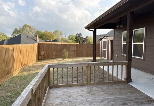 deck with a storage shed, a fenced backyard, and an outbuilding