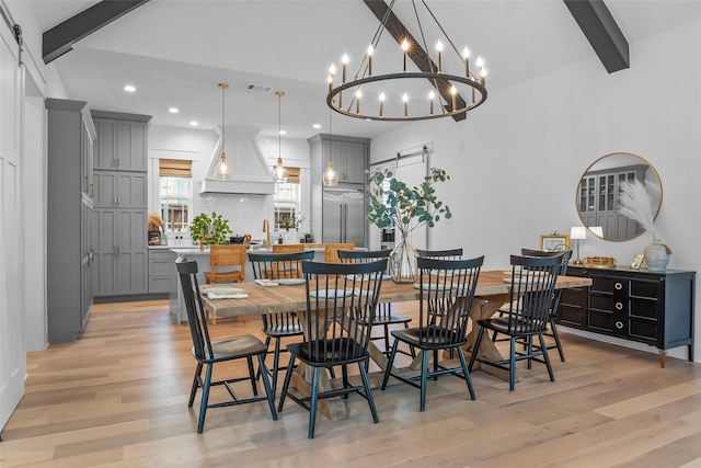dining area with a barn door, a chandelier, and light wood-style floors