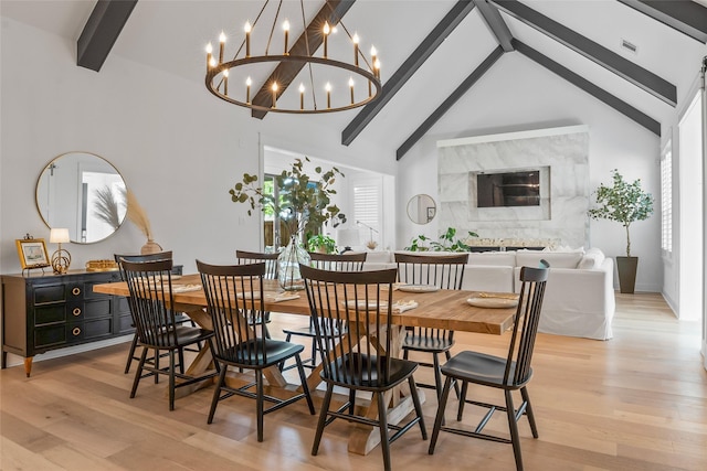 dining area with light wood-style floors, a healthy amount of sunlight, visible vents, beam ceiling, and an inviting chandelier