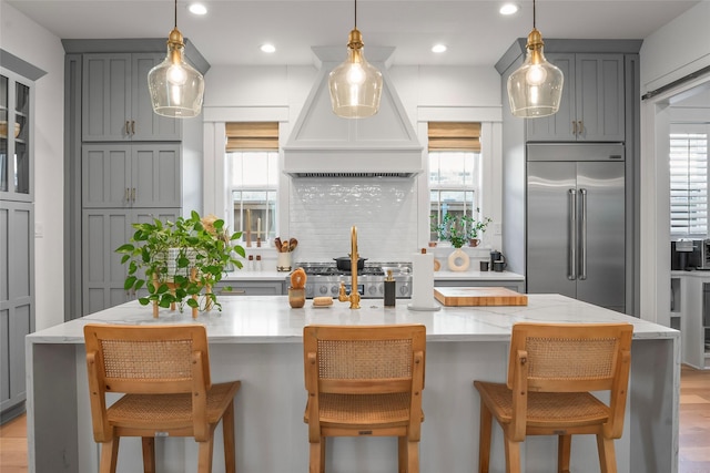 kitchen featuring a wealth of natural light, stainless steel built in refrigerator, premium range hood, and gray cabinets
