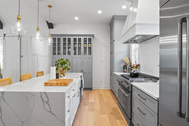 kitchen featuring gray cabinetry, a center island, high end appliances, and premium range hood