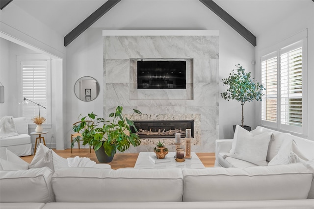 living room with wood finished floors, a premium fireplace, plenty of natural light, and vaulted ceiling with beams