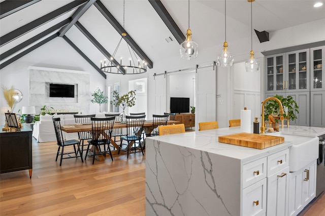 kitchen featuring a sink, open floor plan, a barn door, and lofted ceiling with beams