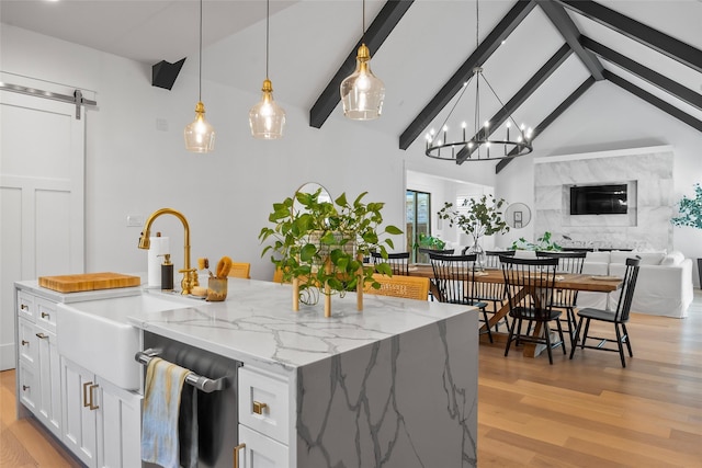 kitchen featuring light wood-style flooring, a sink, a barn door, open floor plan, and dishwasher