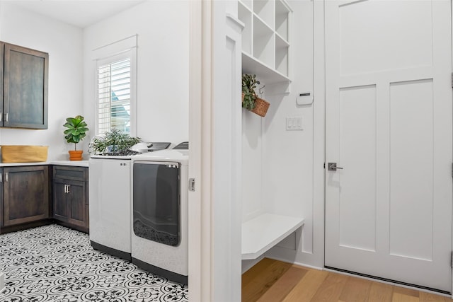 laundry room with cabinet space, washing machine and clothes dryer, and light wood-style floors