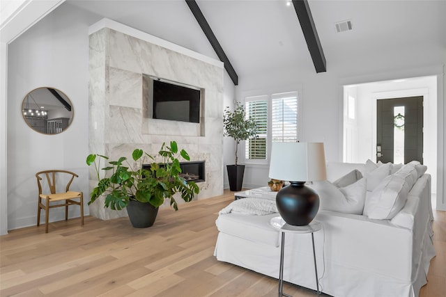 living room with visible vents, lofted ceiling with beams, wood finished floors, and a fireplace