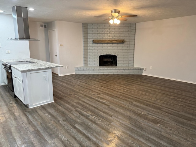 kitchen with wall chimney exhaust hood, a ceiling fan, dark wood-style floors, and visible vents