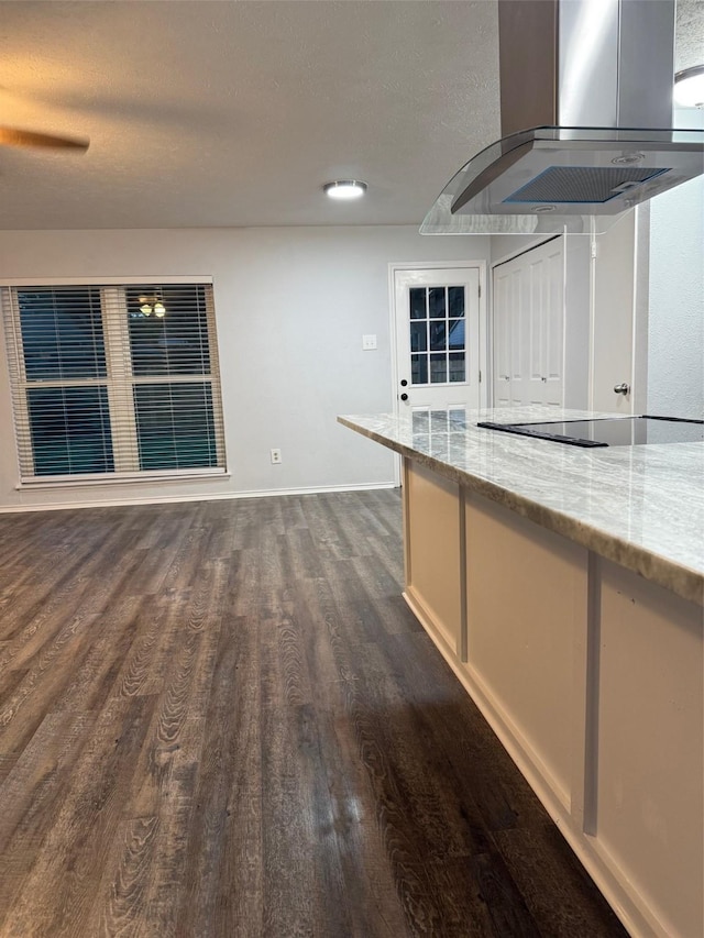 kitchen featuring black electric cooktop, extractor fan, dark wood-type flooring, light stone countertops, and baseboards