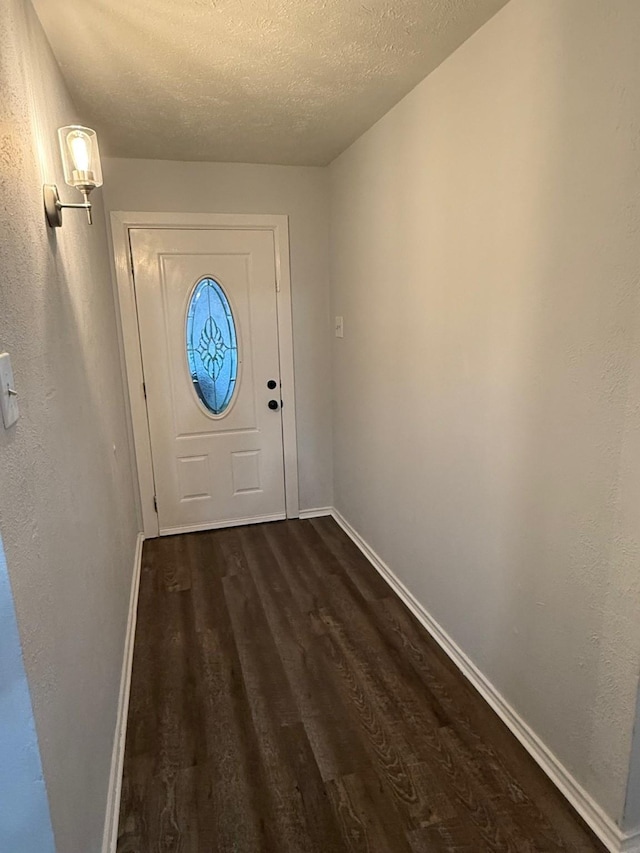 doorway with a textured ceiling, baseboards, and dark wood-style flooring