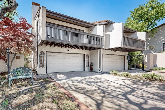 view of front facade featuring concrete driveway, an attached garage, a balcony, and stucco siding