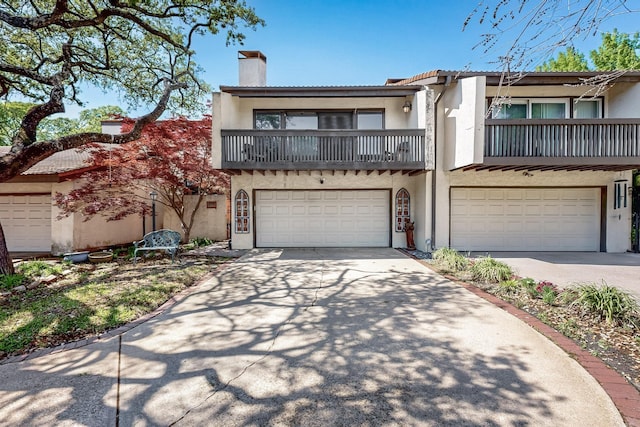 view of front of property with an attached garage, driveway, stucco siding, and a balcony