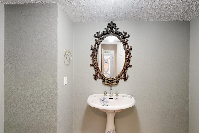 bathroom featuring a textured wall and a textured ceiling