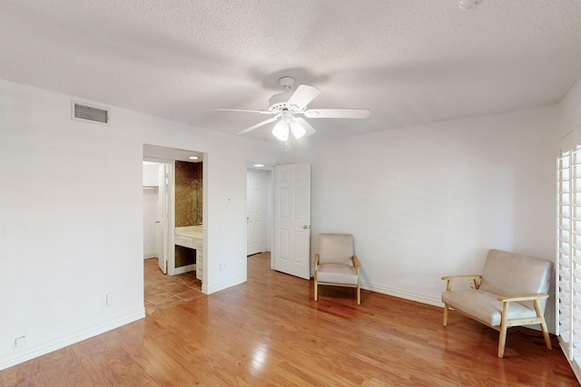 unfurnished room featuring baseboards, a textured ceiling, a ceiling fan, visible vents, and light wood finished floors