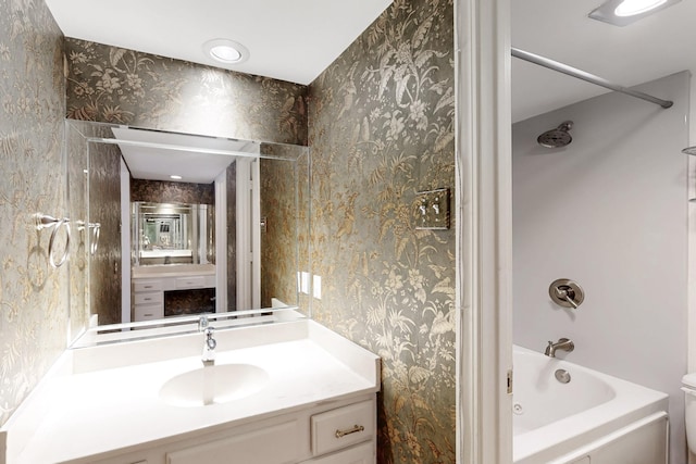 bathroom featuring toilet, vanity, wallpapered walls, and tub / shower combination