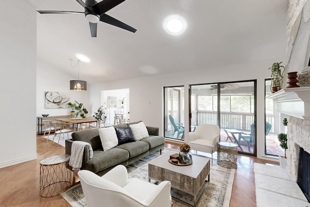 living area featuring light wood-style flooring, a fireplace, a ceiling fan, and vaulted ceiling