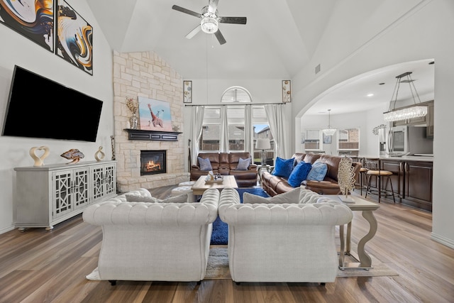 1136 Chickadee Dr, Forney, TX 75126 - living area with ceiling fan, arched walkways, a stone fireplace, wood finished floors, and high vaulted ceiling