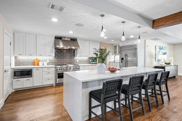 5948 Melshire Dr, Dallas, TX 75230 - kitchen with built in appliances, wall chimney exhaust hood, white cabinets, wood finished floors, and tasteful backsplash