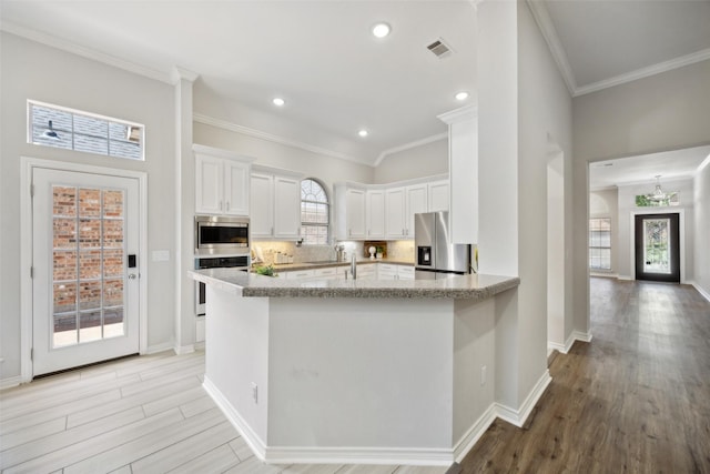 5905 Summer Point Dr, Mckinney, TX 75072 - kitchen featuring white cabinetry, backsplash, appliances with stainless steel finishes, and light wood finished floors