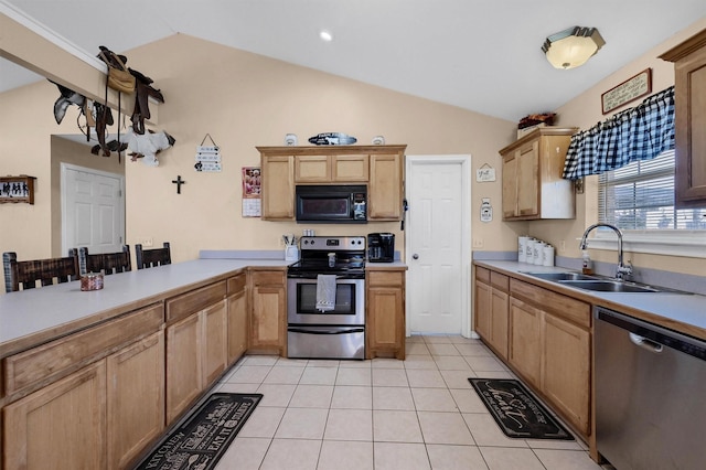 kitchen featuring vaulted ceiling, appliances with stainless steel finishes, light tile patterned flooring, light countertops, and a sink