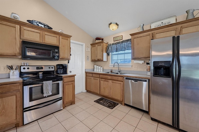 kitchen featuring light tile patterned floors, vaulted ceiling, appliances with stainless steel finishes, light countertops, and a sink