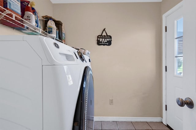 washroom featuring washer and dryer, light tile patterned floors, laundry area, and baseboards