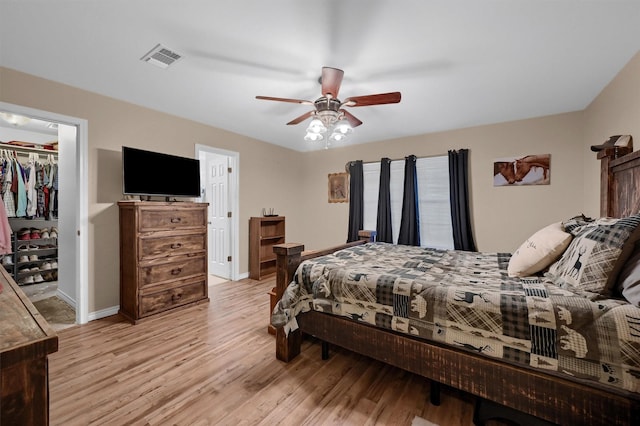 bedroom featuring light wood-type flooring, a closet, a spacious closet, visible vents, and baseboards
