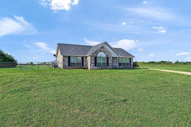 view of front of house with stone siding, fence, and a front lawn