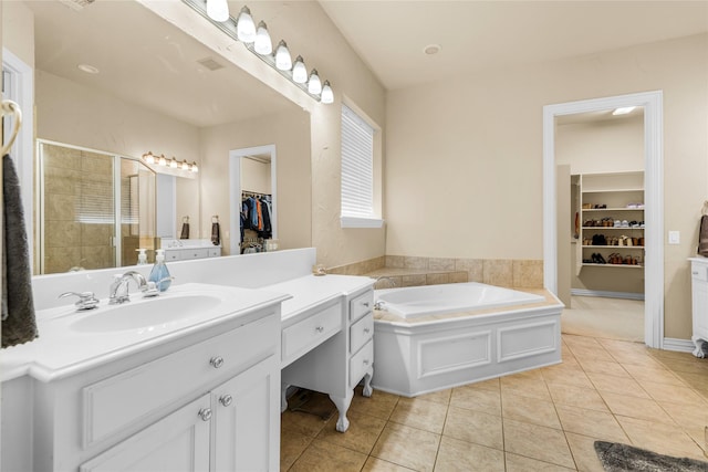 full bath featuring tile patterned floors, a spacious closet, a bath, a shower stall, and vanity