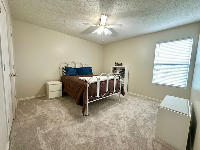 carpeted bedroom featuring a textured ceiling, baseboards, and ceiling fan