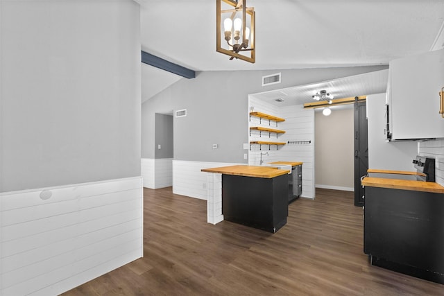 kitchen with a barn door, butcher block countertops, a sink, vaulted ceiling with beams, and visible vents