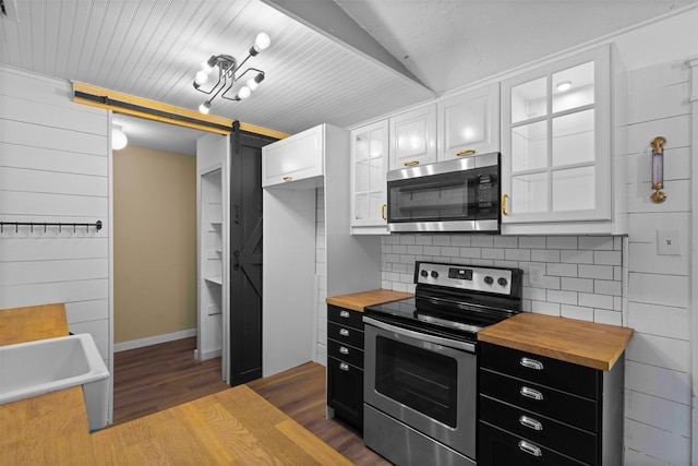 kitchen with dark cabinetry, wood counters, white cabinetry, and appliances with stainless steel finishes
