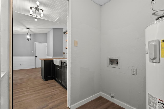 clothes washing area featuring a sink, electric water heater, washer hookup, wood finished floors, and laundry area