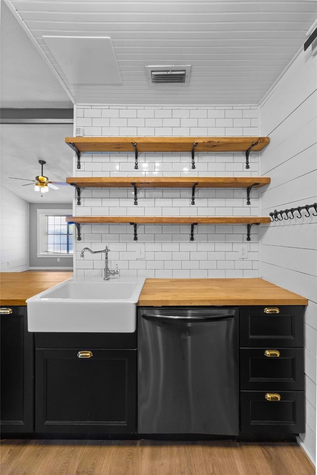 kitchen featuring dark cabinets, dishwasher, and wooden counters