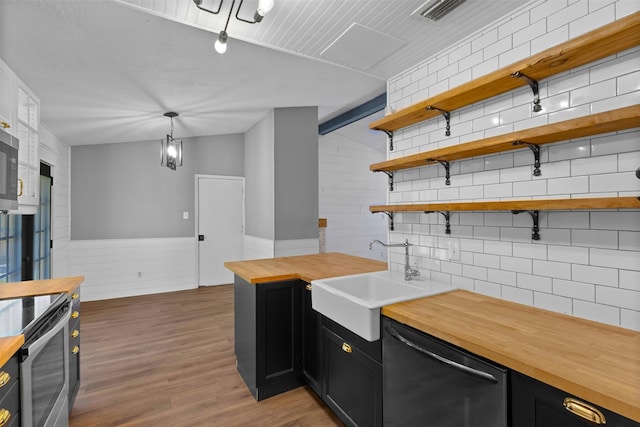 kitchen featuring dark cabinets, dishwasher, a sink, wood counters, and stainless steel range with electric stovetop