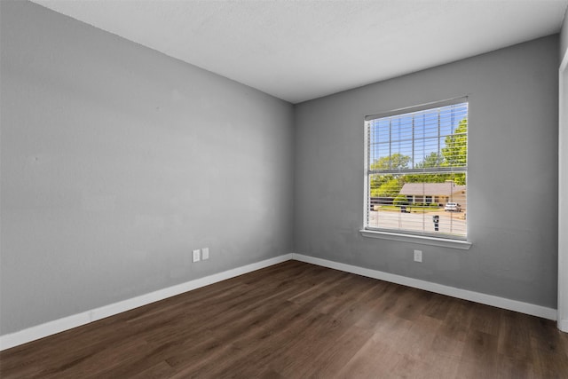 empty room with baseboards and dark wood-type flooring