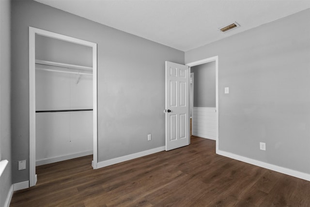 unfurnished bedroom featuring visible vents, baseboards, wood finished floors, and a closet