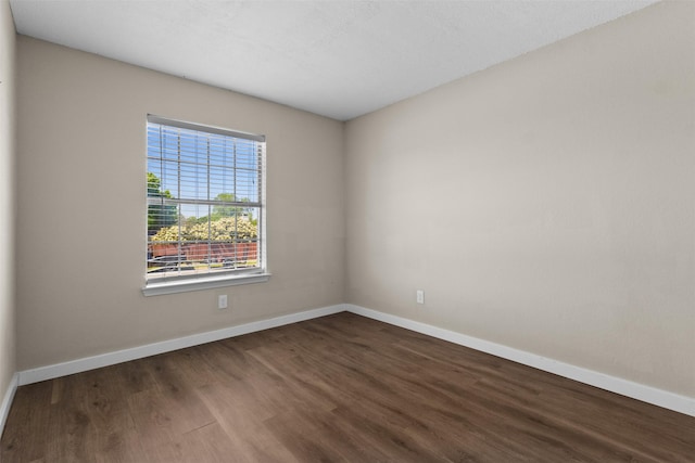 spare room featuring baseboards and wood finished floors