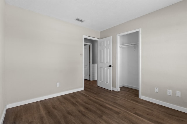 unfurnished bedroom with baseboards, visible vents, a closet, and dark wood-style flooring